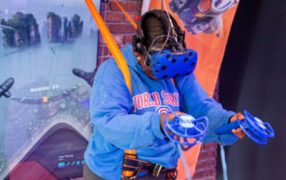 a woman experiencing VR flight with a safety harness and interactive controls